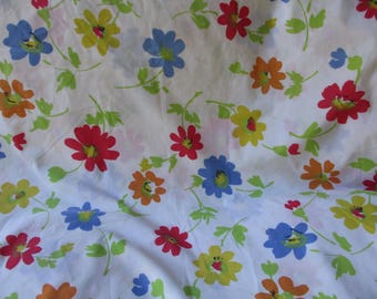 Puede incluir: Tela blanca con un patrón repetitivo de flores de colores. Las flores son rojas, azules, amarillas y naranjas. La tela tiene un aspecto vintage.
