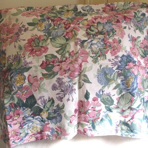 May include: A rectangular pillowcase featuring a dense floral pattern on a white background. The design includes clusters of pink, blue, and yellow flowers with green leaves, creating a continuous botanical print across the entire fabric surface.