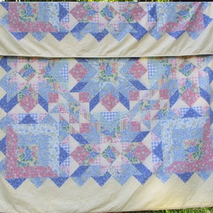 May include: A patchwork quilt with a yellow background and a central design of blue, pink, and white floral patterns. The quilt is made of various fabrics with different patterns and textures.
