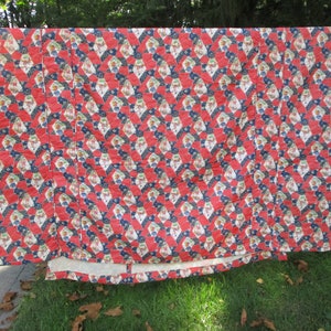 Puede incluir: Una colcha con estampado geométrico rojo, blanco y azul. La colcha está hecha de tela de algodón y tiene un respaldo blanco.
