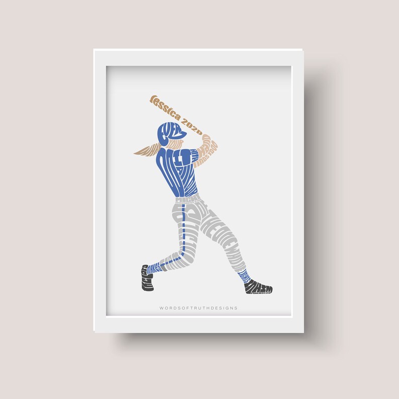 May include: A white framed print of a baseball player in a blue and gray uniform, swinging a bat. The player's uniform is made up of words, including "Jessica 2020". The print is by Words of Truth Designs.
