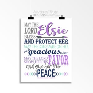 Puede incluir: Un diseño de arte de pared imprimible blanco con un esquema de color morado y turquesa. El diseño presenta una cita de Números 6:24-26 NLT: "Que el Señor la bendiga y la proteja. Que el Señor le sonría y sea misericordioso con ella. Que el Señor le muestre su favor y le dé su paz." El nombre Elsie está escrito en morado en la parte superior del diseño.