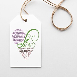 May include: A white tag with a green and purple design that says "Love is patient and kind, love does not envy or boast, it is not arrogant or rude, it does not insist on its own way; it is not irritable or resentful: it does not rejoice at wrongdoing, but rejoices with the truth" and "bears-believes-hopes endures -ALL THINGS- Love never ends".