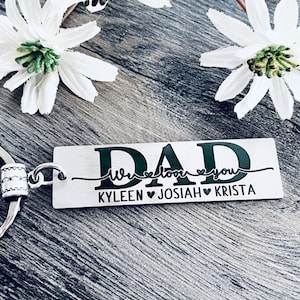 May include: Silver keychain with a black rectangular tag that reads "DAD We love you KYLEEN JOSIAH KRISTA".