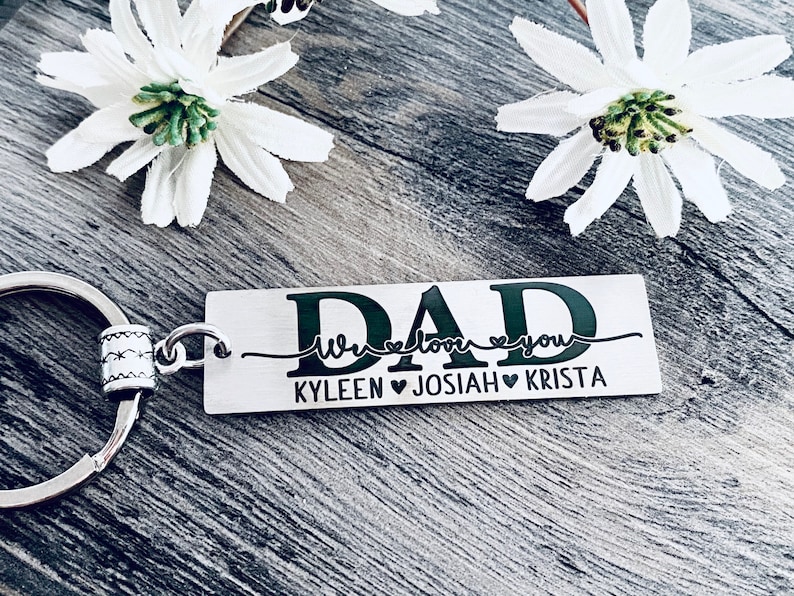 May include: Silver keychain with a black rectangular tag that reads "DAD We love you KYLEEN JOSIAH KRISTA".