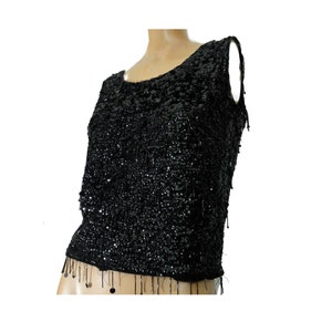 May include: A black sleeveless top with a sequined design and a fringe trim.
