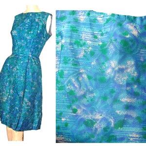 May include: A sleeveless blue dress with a white and green abstract print. The dress has a fitted bodice and a full skirt.
