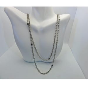 Op de afbeelding: Een zilveren ketting met vierkante accenten. De ketting is gelaagd en heeft een delicaat kettingontwerp.