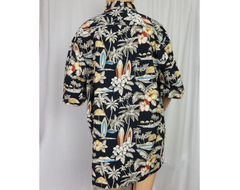 May include: A black short-sleeved button-down shirt with a tropical print featuring palm trees, flowers, and surfboards.