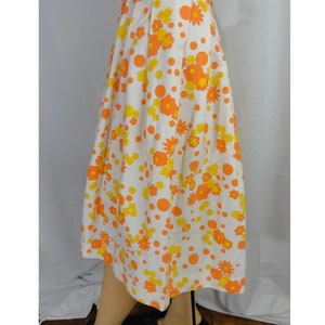 May include: A white midi skirt with a floral print featuring orange and yellow flowers and orange polka dots.