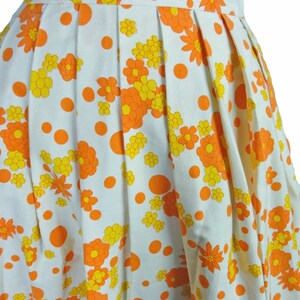 May include: A white skirt with a pattern of orange and yellow flowers and orange polka dots.