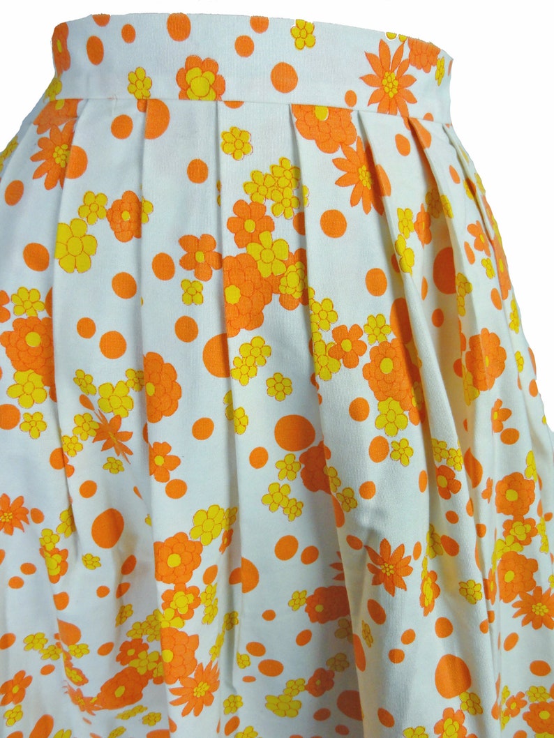 May include: A white skirt with a pattern of orange and yellow flowers and orange polka dots.