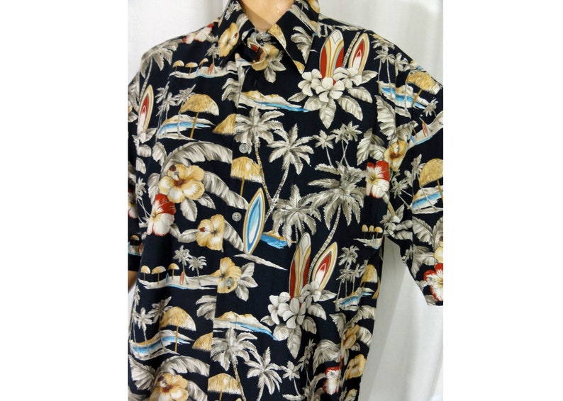 May include: A black short-sleeved button-down shirt with a tropical print featuring palm trees, flowers, and surfboards.
