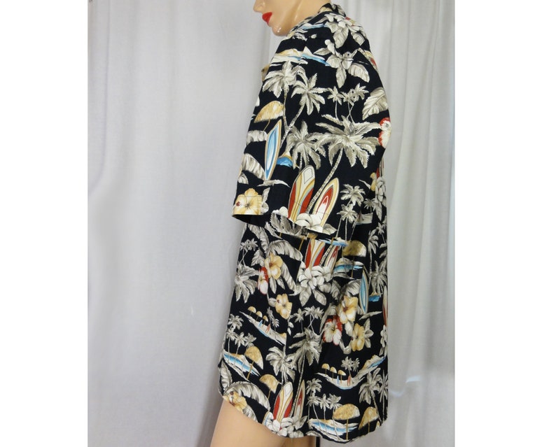 May include: A black short-sleeved button-down shirt with a tropical print featuring palm trees, surfboards, and flowers.