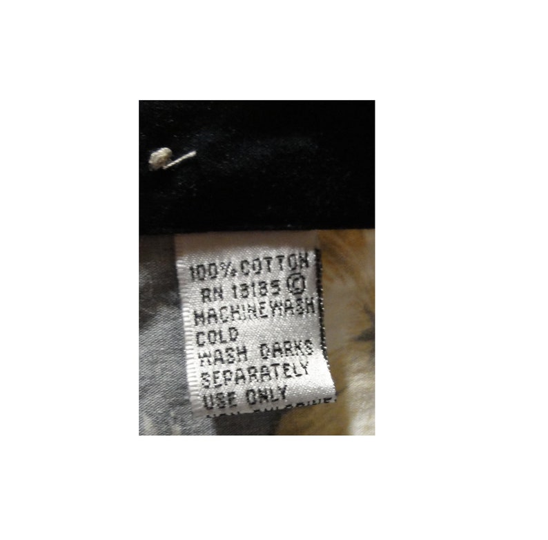 May include: White care label with black text that reads "100% cotton RN 13185 Machine Wash Cold Wash Darks Separately Use Only".