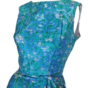 May include: A sleeveless blue and green patterned dress with a white background. The dress has a tie at the waist.