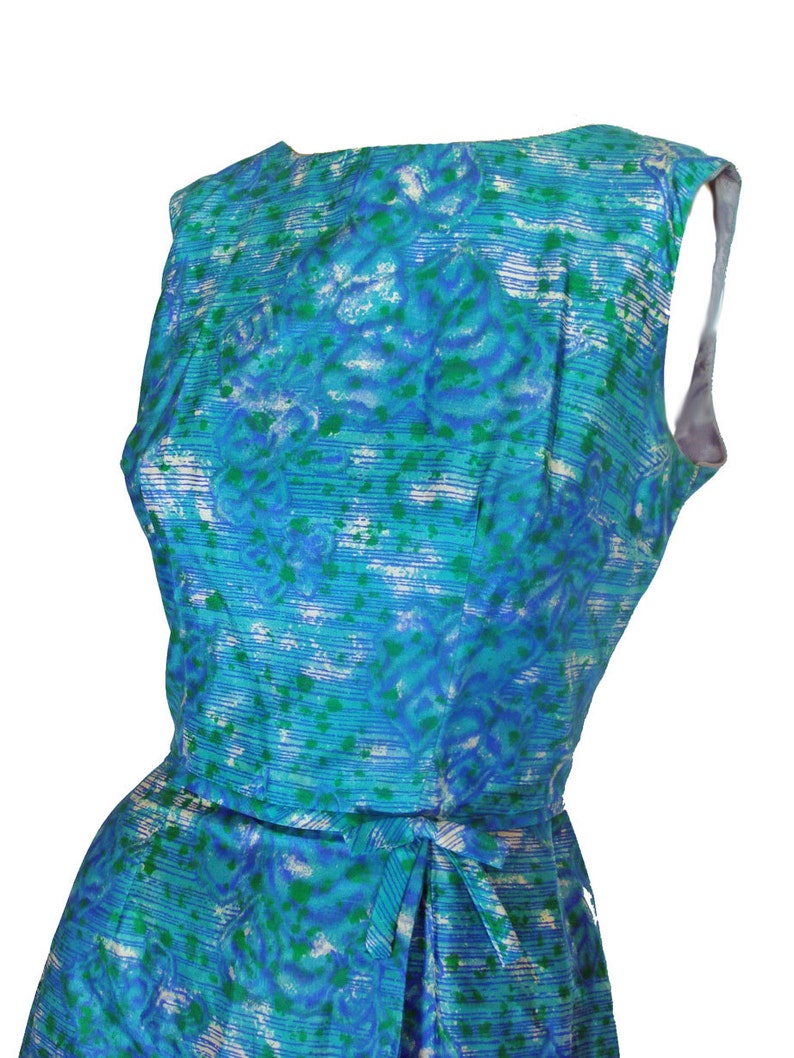 May include: A sleeveless blue and green patterned dress with a white background. The dress has a tie at the waist.