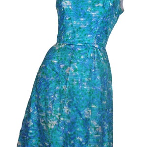 May include: A sleeveless blue and green patterned dress with a white background. The dress has a fitted bodice and a slightly flared skirt. The dress has a tie at the waist.