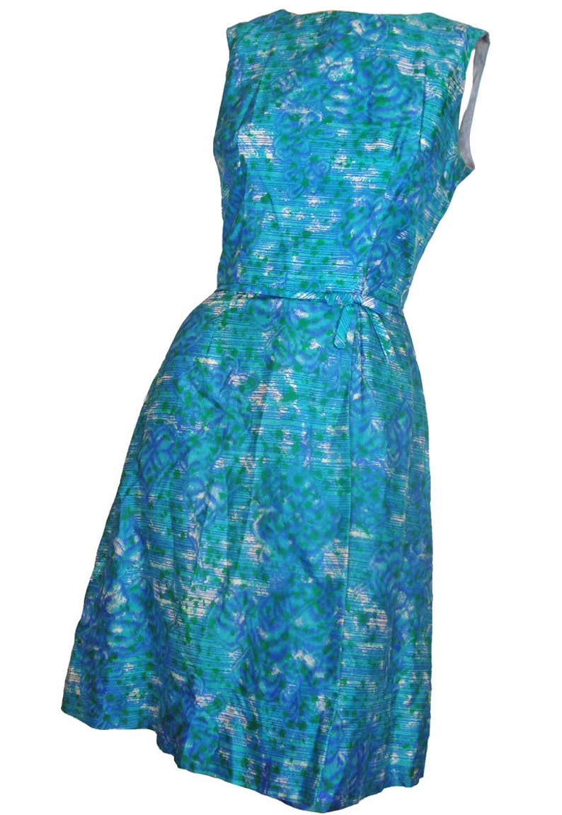May include: A sleeveless blue and green patterned dress with a white background. The dress has a fitted bodice and a slightly flared skirt. The dress has a tie at the waist.