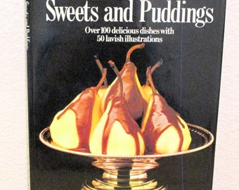 May include: A cookbook titled "Sweets and Puddings" with a yellow and black cover featuring a photo of pears in a silver bowl with chocolate sauce. The text "Over 100 delicious dishes with 50 lavish illustrations" is printed below the title.
