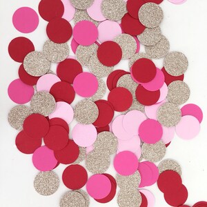 May include: A pile of red, pink and gold confetti circles. The confetti is made of paper and glitter.