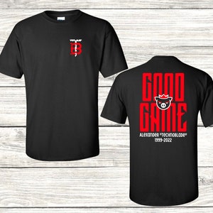 May include: Black t-shirt with a red "Good Game" graphic featuring a pig wearing a crown. The text "Alexander "Technoblade" 1999-2022" is below the graphic. The front of the shirt has a small red "TB" logo.