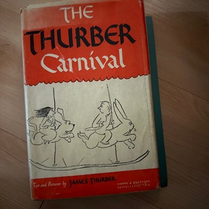 May include: The cover of a red hardcover book titled "The Thurber Carnival" with black text. The book features a black and white illustration of a carousel with three figures riding on it.