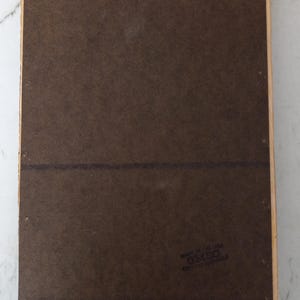 May include: The back of a wooden picture frame with a brown backing and a label that reads "Made in the UK, D.M.S.O. Registered Design".