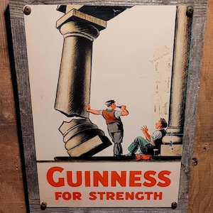 May include: Vintage Guinness advert sign in a wooden frame. The sign shows an illustration of two men and a broken column, with the words "GUINNESS FOR STRENGTH" in red.