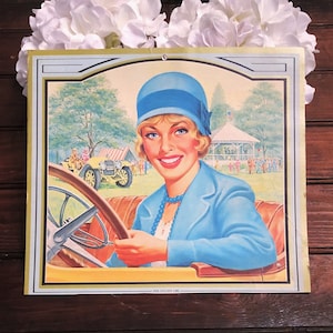 May include: A vintage advertisement featuring a woman in a blue hat and dress driving a yellow car. The text "The Golden Car" is visible at the bottom of the image.