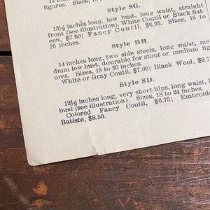 May include: A vintage price list for corsets, featuring different styles and sizes. The list includes details like bust measurements, waist measurements, and fabric options. The text mentions "White Coutil", "Black Sat-een", "Gray Coutil", "Black Wool", "Colored Fancy Coutil", and "Embroidered Batiste".