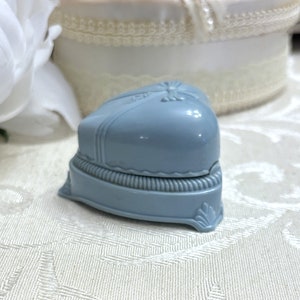 May include: A light blue heart-shaped ring box with a raised design and a scalloped edge.