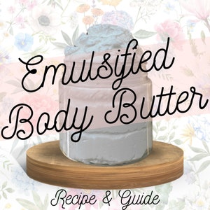May include: A glass jar filled with a light gray emulsified body butter, sitting on a wooden round base. The jar is labeled "Emulsified Body Butter" in black cursive lettering. The background is a floral pattern.