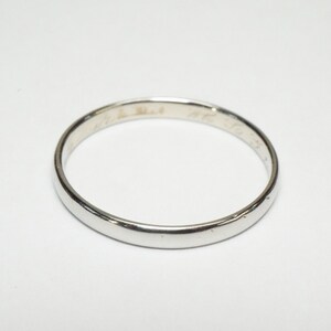 May include: A simple silver band ring with a subtle inscription on the inside.