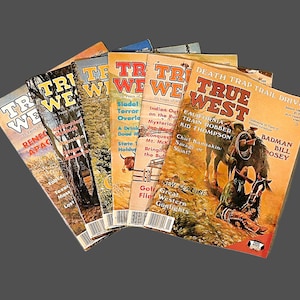 May include: A collection of vintage "True West" magazines. The covers feature illustrations of cowboys, landscapes, and text. The magazines are in various colors, including orange, yellow, and green, with titles like "Death Trap Trail Drive" and "Renegade Apache".
