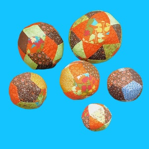 May include: Six colourful patchwork fabric balls with different patterns and colours, including orange, brown, green, and blue.