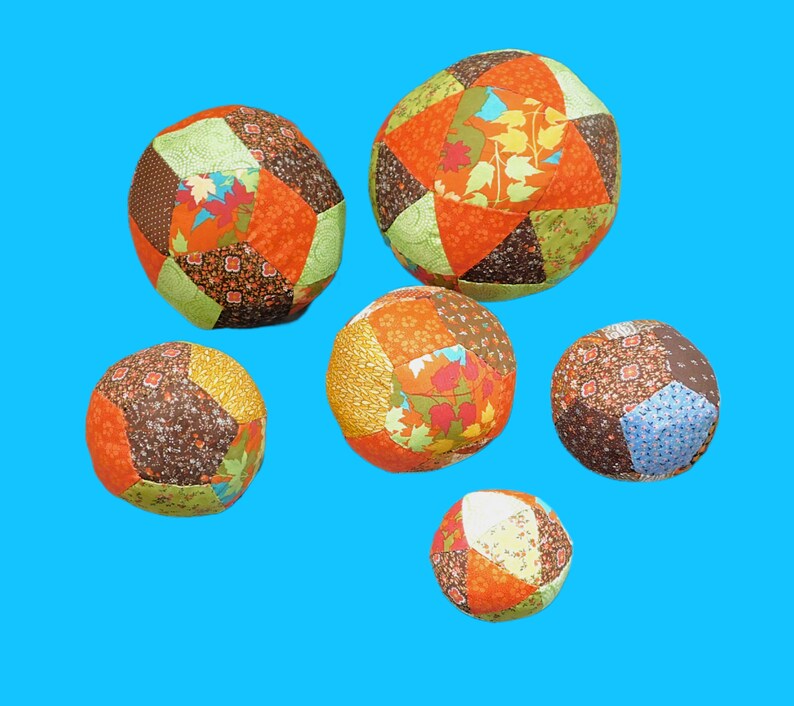 May include: Six colourful patchwork fabric balls with different patterns and colours, including orange, brown, green, and blue.