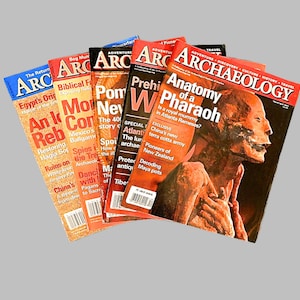 May include: A stack of six Archaeology magazines with red and white covers. The top magazine features a close-up of a Pharaoh's mummy with the title "Anatomy of a Pharaoh".