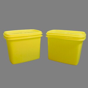 May include: Two yellow plastic containers with lids. The containers are rectangular and have a smooth surface.