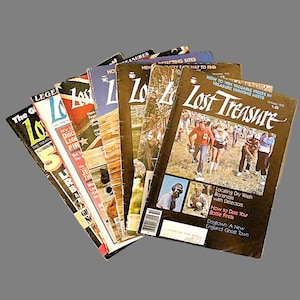 May include: A stack of vintage "Lost Treasure" magazines. The covers feature images of people treasure hunting and articles about finding lost items. The magazines are in various colors and show signs of wear.