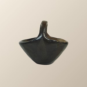 May include: A small, black ceramic basket with a handle. The basket is glazed and has a smooth finish.