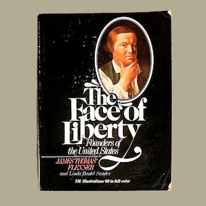 May include: A black book cover with a portrait of a man in a white shirt and a black jacket. The title of the book is "The Face of Liberty" and the subtitle is "Founders of the United States". The authors are James Thomas Flexner and Linda Bantel Samter. The book has 136 illustrations, 60 of which are in full color.