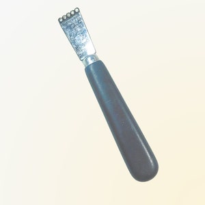 May include: A silver citrus zester with a black plastic handle. The zester has a serrated edge and is used to zest citrus fruits.