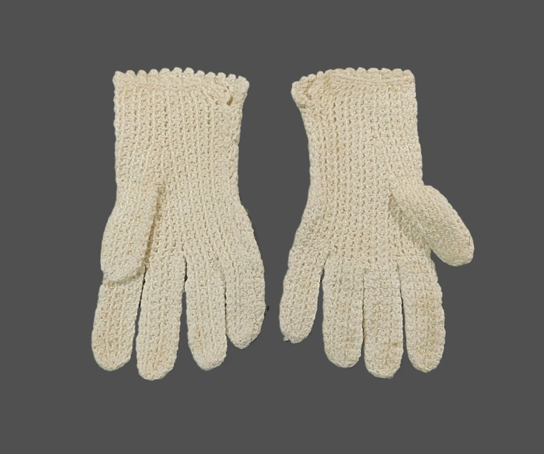 May include: A pair of white crocheted gloves. The gloves have a delicate, lacy pattern and are made of a soft, lightweight yarn.