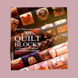 May include: A book titled "501 Quilt Blocks: A Treasury of Patterns for Patchwork & Appliqué" by Better Homes and Gardens. The cover features a colorful display of quilt blocks, including a red cardinal, floral patterns, and geometric designs.
