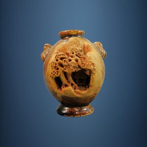 May include: A small, round, brown ceramic vase with a carved design of trees and a house. The vase has a wide mouth and a small base.