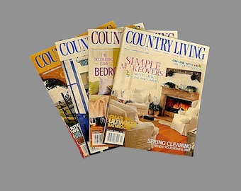 May include: Four copies of Country Living magazine stacked on top of each other. The top magazine features a fireplace and the text "Simple Makeovers" and "Spring Cleaning". The magazine below it features a bathroom and the text "Create the Ultimate Bathroom". The magazine below that features a bedroom and the text "The Decorating Issue Bedroom". The bottom magazine is partially visible and features a kitchen and the text "Kitchen We Love Your Specs".