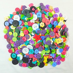 May include: A large collection of colorful plastic buttons in various shapes and sizes. The buttons are arranged in a random pattern and include a variety of colors, including red, blue, green, yellow, and purple.