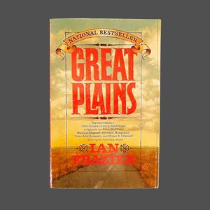 May include: A book cover with a red and white title "Great Plains" and the author's name "Ian Frazier" in red text. The cover features a photo of a road leading into a field of tall grass.