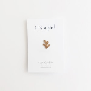 Op de afbeelding: Een witte kaart met de tekst "it's a pin!" en een klein gouden bladspeldje. De kaart heeft ook de tekst "a jar of pickles" en het websiteadres "www.ajarofpickles.com".